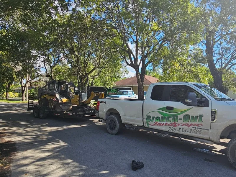 Branch-Out pickup truck and equipment trailer parked at a job site